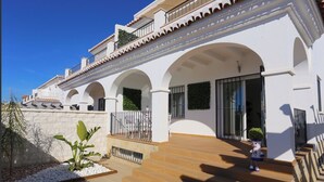A white building with multiple arches and a wooden deck. - Noza Beach (Valle-Niza)