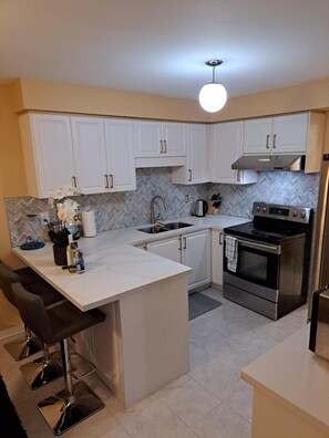 A modern kitchen with white cabinets, a stainless steel stove, and a herringbone-patterned backsplash.