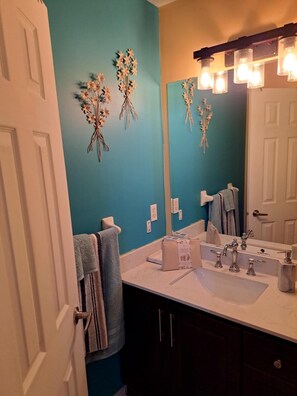 A bathroom with a teal wall, a white sink, a mirror, and a towel rack. - Luxury getaway (Brampton)