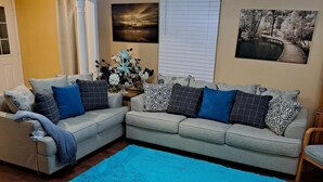 A living room with a blue rug, two sofas with patterned cushions, a decorative vase, and a painting on the wall. - Luxury getaway (Brampton)
