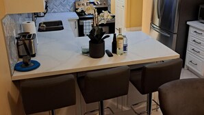 A compact kitchen with a central island, bar stools, a refrigerator, and a microwave. - Luxury getaway (Brampton)