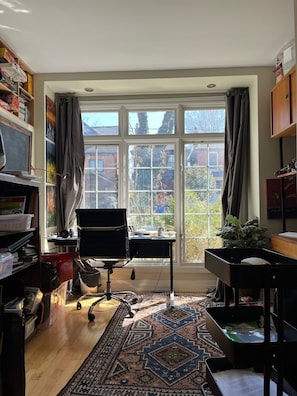 Work in comfort with a desk, chair, and computer, surrounded by a bookshelf and a small plant.