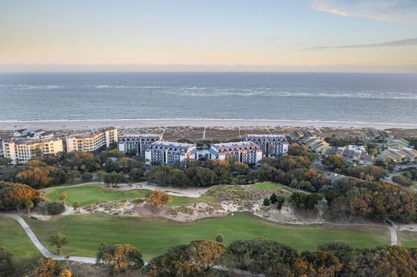 Un hotel frente al mar con varias edificaciones, un campo de golf y vistas a la playa.