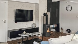 Un soggiorno moderno con una TV a schermo piatto, un camino, un divano e un tavolino da caffè.