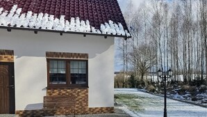 Una casa con tetto in tegole rosse, una parte inferiore in mattoni e un muro esterno bianco.
