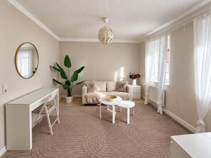 A modern living room with a sofa, coffee table, and a large plant.