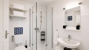 A modern bathroom with a glass-enclosed shower, a white sink, and a toilet.