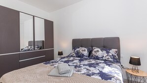 Une chambre à coucher avec un lit, un grand miroir, une table de chevet et une lampe.