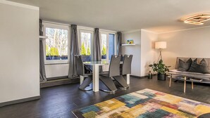 A modern living room with a dining area, large windows, a colorful rug, and a sofa. - 1 bedroom gorgeous home in Stralsund (Stralsund)
