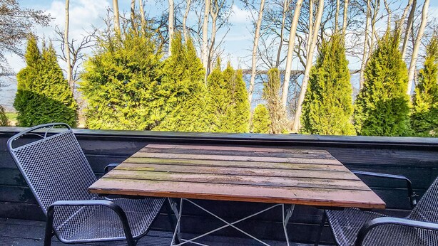 An outdoor seating area with a wooden table and metal chairs, overlooking a forested area with tall trees. - 1 bedroom gorgeous home in Stralsund (Stralsund)