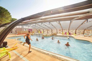 An indoor swimming pool with a covered roof, clear water, and a few people swimming. - Proche d'Argelès | Parc Aquatique | Camping 4* (Laroque des Albères)