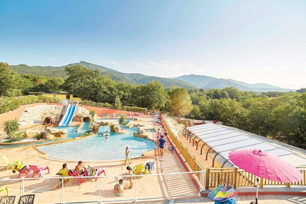 A pool area with a water slide, lounge chairs, and a covered deck. - Proche d'Argelès | Parc Aquatique | Camping 4* (Laroque des Albères)