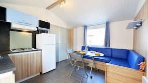 Una cocina compacta con estufa a gas, un refrigerador blanco y un sofá azul.