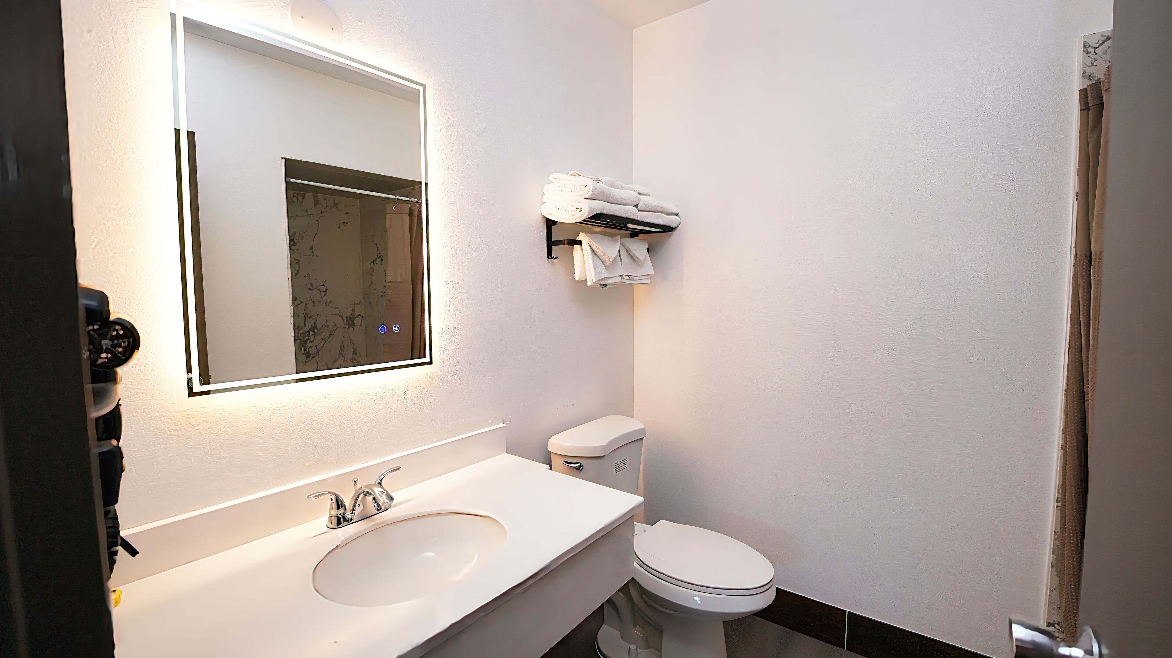 Une salle de bain moderne avec un lavabo blanc, des toilettes et un miroir.
