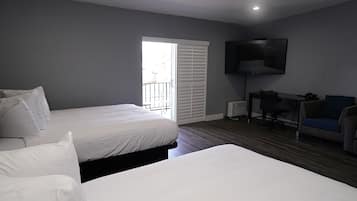Une chambre avec deux lits, un bureau, une chaise, un téléviseur et une fenêtre avec des stores.