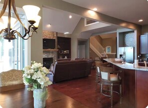 A spacious living area with a fireplace, a dining table with chairs, and a kitchen area with a bar.
