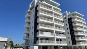 A multi-story residential building with balconies, large windows, and a clear sky.
