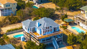 Una casa gran de dos pisos amb terrassa, piscina i una escala que condueix al pis superior.
