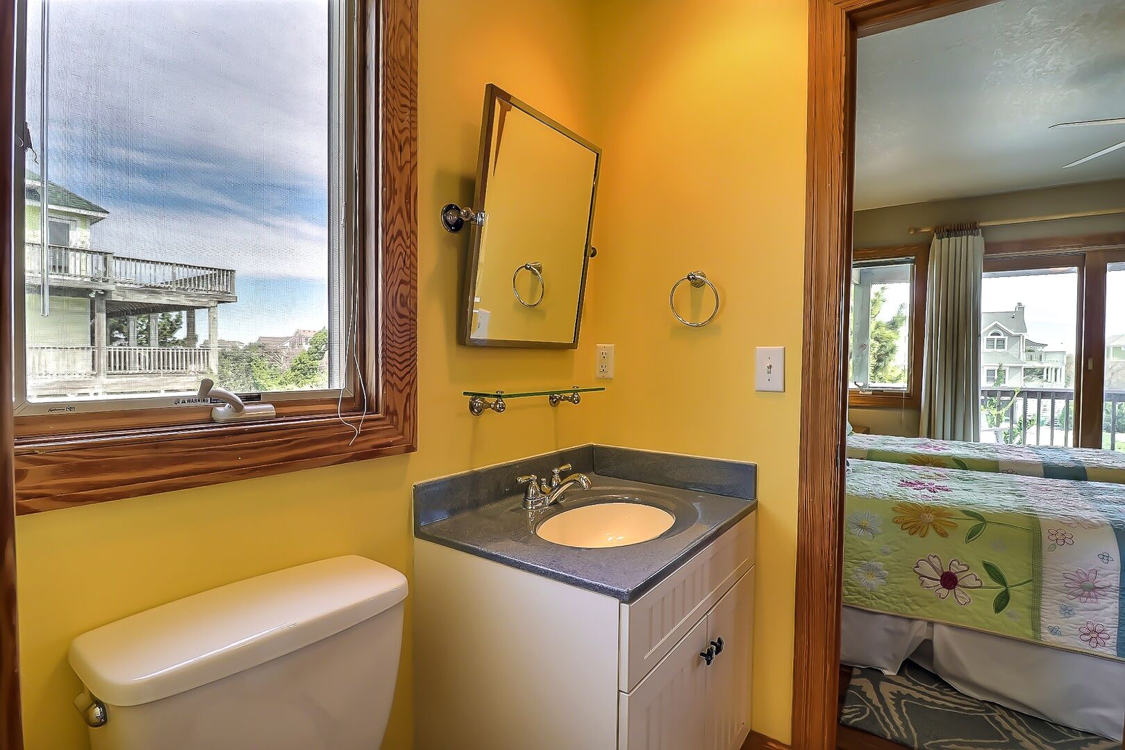 A bathroom with a toilet, sink, and window.