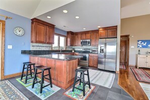 Una cocina moderna con armarios de madera, un refrigerador de acero inoxidable y una isla central con taburetes.