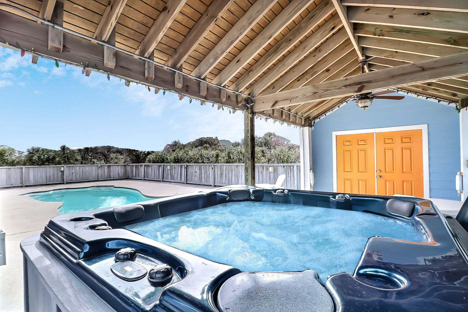 Een achtertuin met een jacuzzi, een zwembad en een overdekt terras.