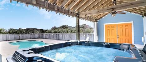 Een achtertuin met een jacuzzi, een zwembad en een overdekt terras.