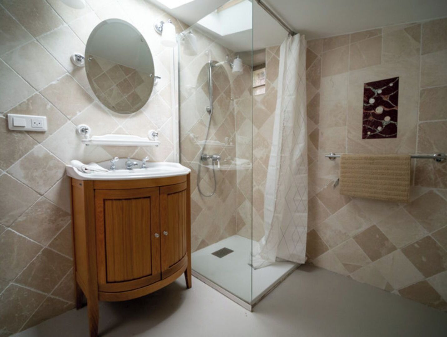 A modern bathroom with a wooden vanity, a glass shower enclosure, and a decorative tile backsplash.