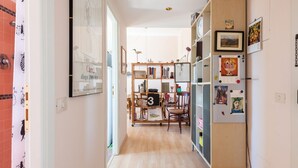 Un pasillo con una estantería de madera, un refrigerador con imanes y una puerta con ilustraciones de gatos.