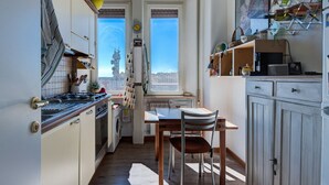 Una cocina pequeña con comedor, lavadora y vista a la ciudad a través de una ventana.