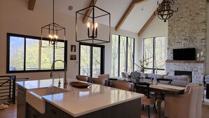 Une cuisine spacieuse avec un grand îlot central, un coin repas avec un canapé et une cheminée en pierre.
