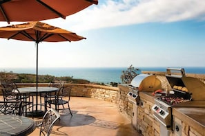 Eine Außenpatio mit einer Steinmauer, einem Grill und einem Tisch mit Stühlen.