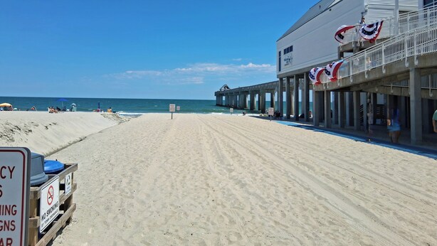 A beachside building with a pier extending into the water, featuring a sign indicating no smoking by town ordinance.
