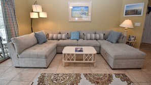 A living room with a sectional sofa, a coffee table, and two wall-mounted lamps.