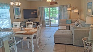 A spacious living area with a dining table, chairs, a sofa, and a television.
