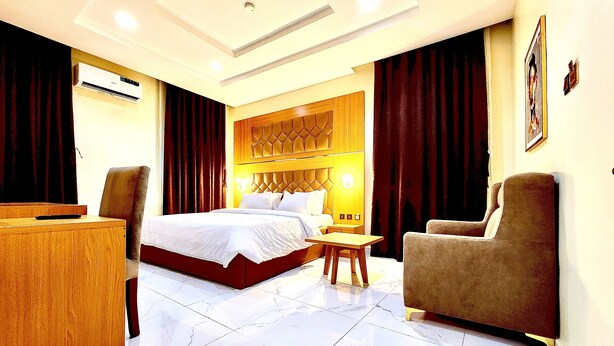 Een hotelkamer met een groot bed, een houten bureau, een stoel en een klein tafeltje.