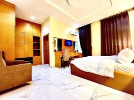 Una habitación de hotel con cama, escritorio, silla y armario.