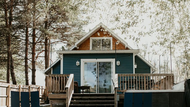 A cabin with a deck, two Adirondack chairs, and a fire pit. - Lakefront Chalet - Dog Friendly w/ Hot Tub, Firepit and Kayaks (Six Lakes)