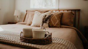A neatly made bed with a woven tray holding two white mugs and a small vase with dried flowers. - Lakefront Chalet - Dog Friendly w/ Hot Tub, Firepit and Kayaks (Six Lakes)