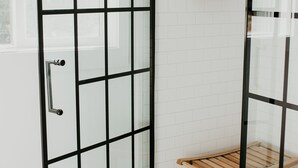 A shower area with a glass door, a wooden bench, and shelves with toiletries. - Lakefront Chalet - Dog Friendly w/ Hot Tub, Firepit and Kayaks (Six Lakes)