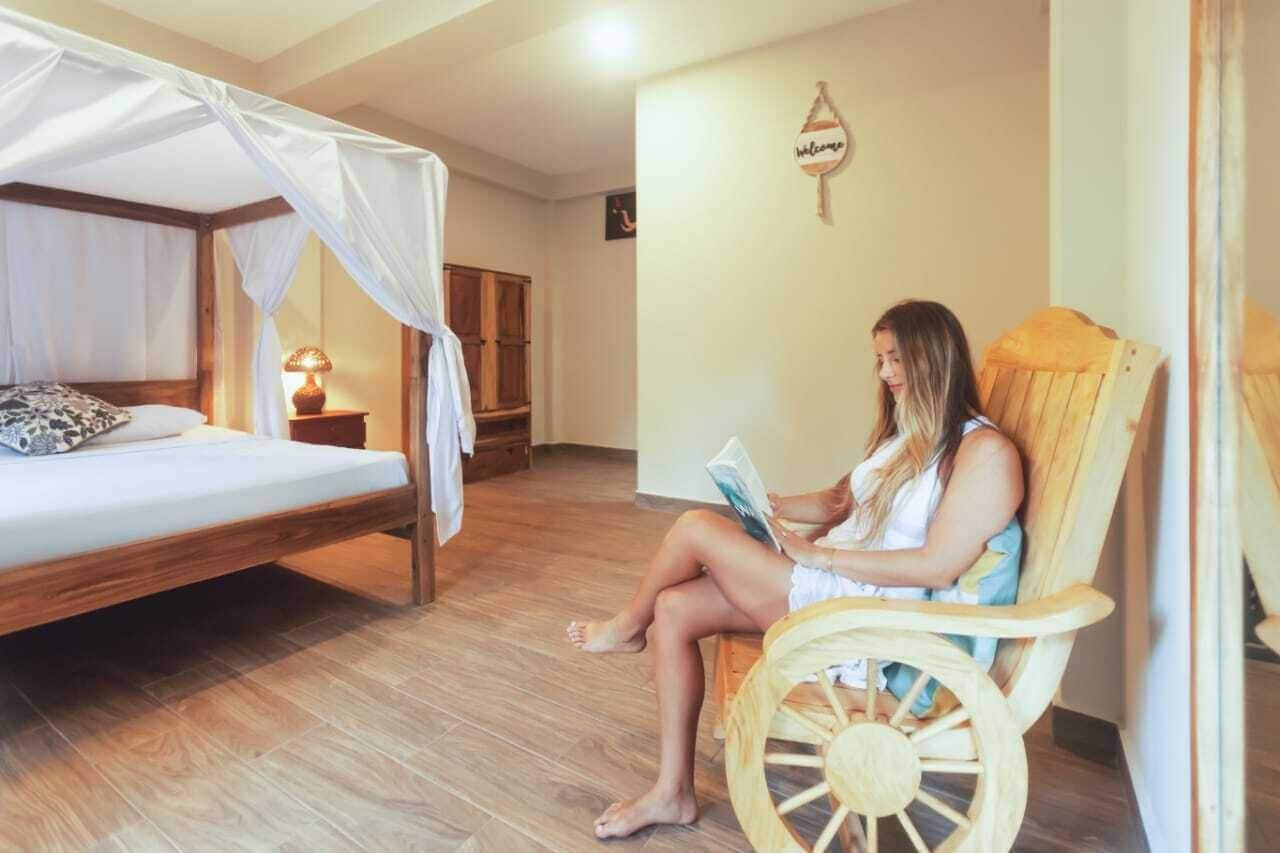 Una habitación con una cama, una silla de madera y una mesita con una lámpara.