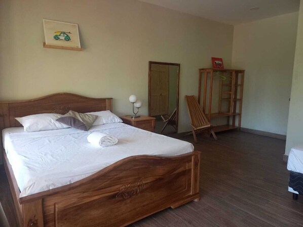 Une chambre à coucher avec un lit en bois, une table de chevet avec une lampe, une chaise, une armoire et un miroir au mur.