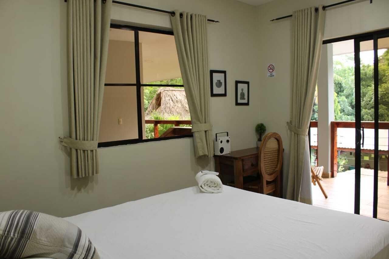 Une chambre d’hôtel avec un lit, un bureau, une chaise et une vue sur l’extérieur.