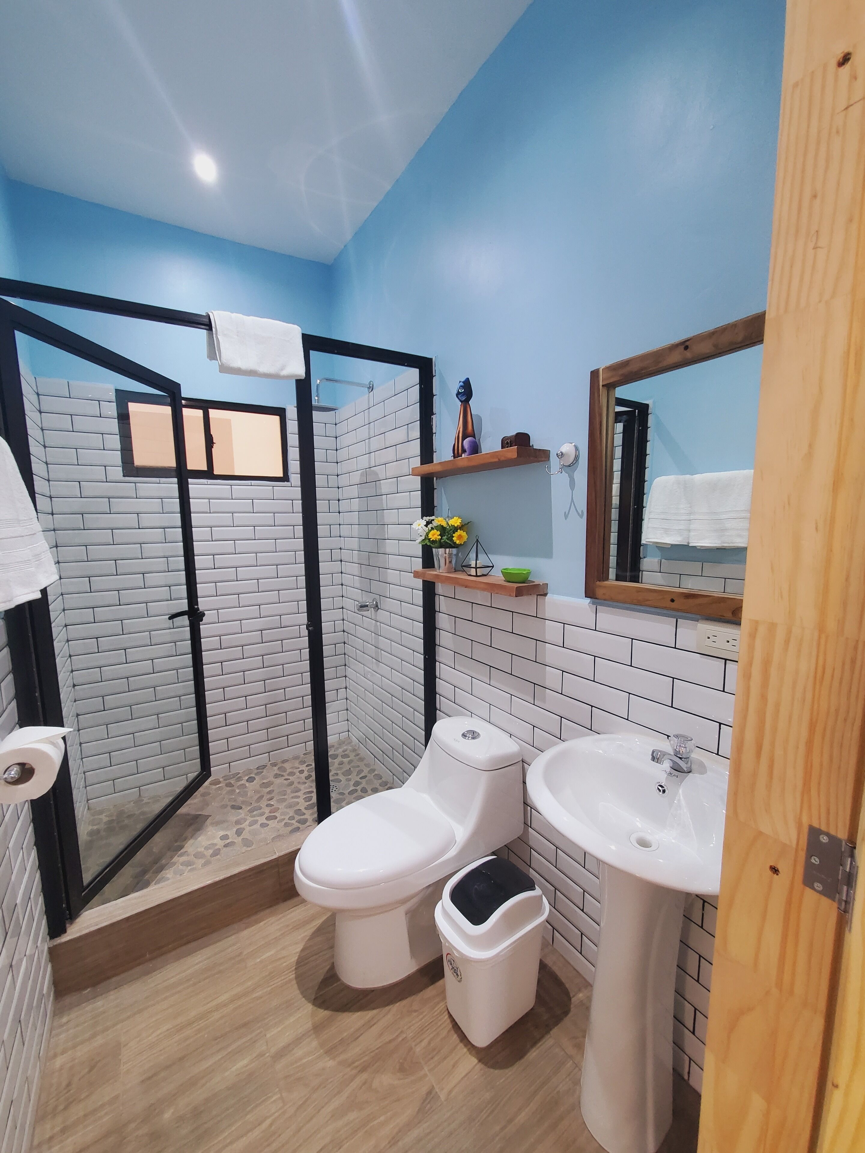 Un bany modern amb dutxa, dues vàteres, un lavabo i un mirall.