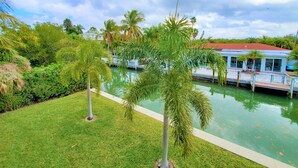 Un área de piscina con palmeras, un muelle y un edificio de techo rojo.
