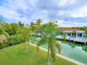 A pool area with palm trees, a dock, and a building with a red roof.