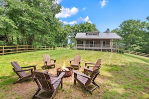Eine Holzterrasse mit Adirondack-Stühlen, einer Feuerstelle und einem Haus mit Veranda.