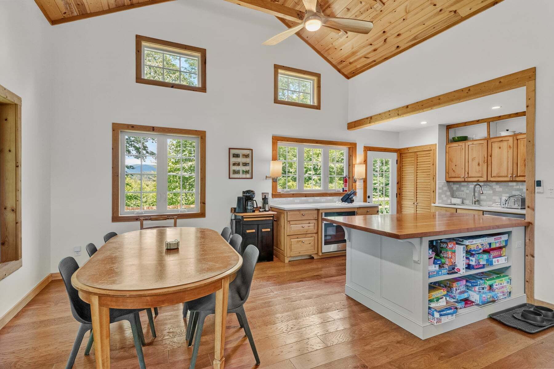 Une cuisine spacieuse avec des meubles en bois, un îlot central et de grandes fenêtres offrant une vue sur la verdure.