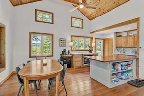 A spacious kitchen with wooden cabinets, a central island, and large windows offering views of greenery.