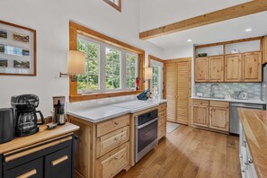 A modern kitchen with wooden cabinets, a large window, and a built-in oven.