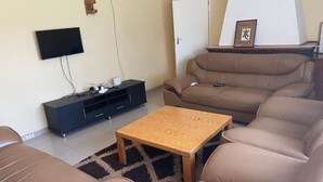 Una sala de estar con un sofá de cuero marrón, una mesa de centro de madera, un mueble de entretenimiento negro y un televisor montado.